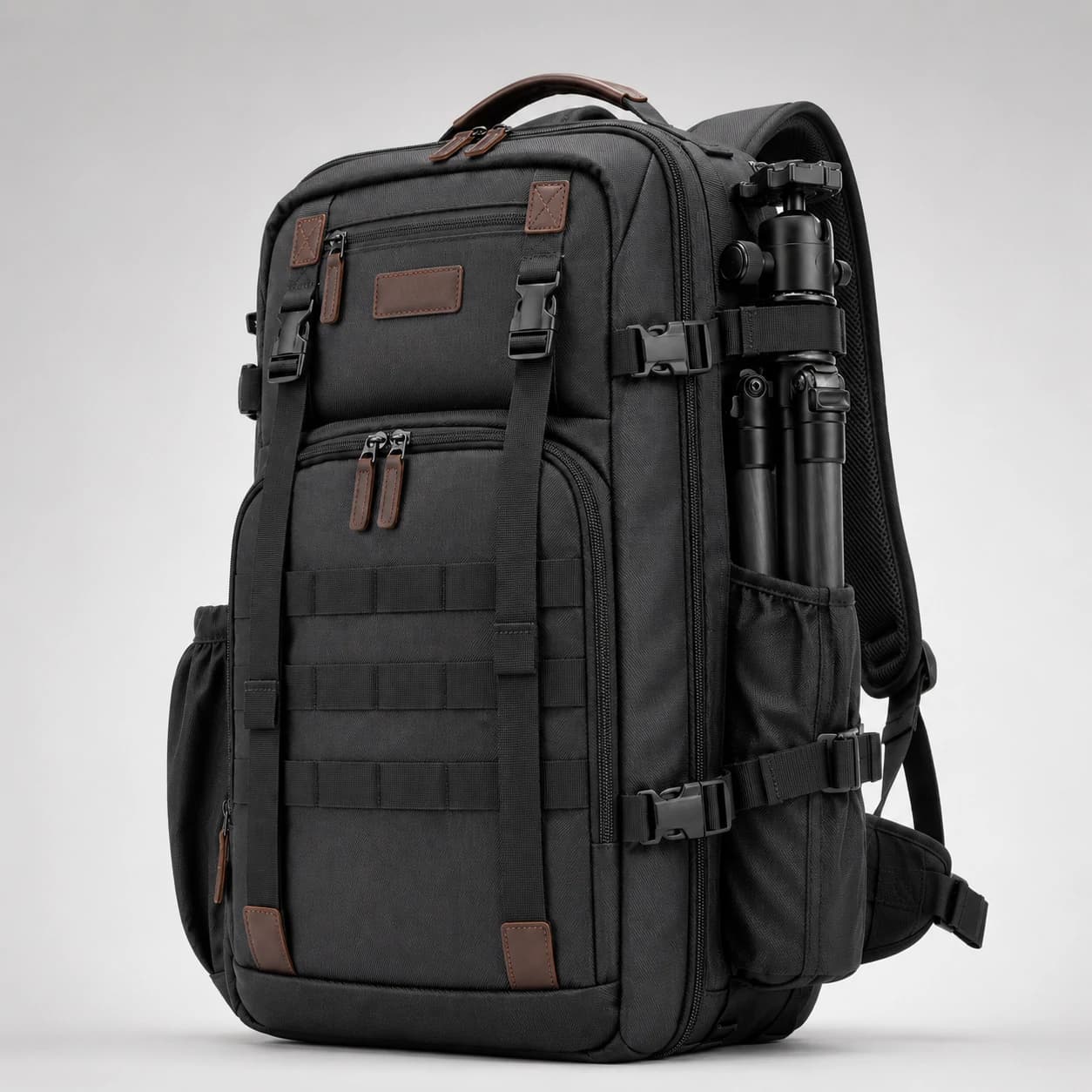 Front three-quarter view of a black gear backpack with webbing, zip compartments, and a tripod attached at the side